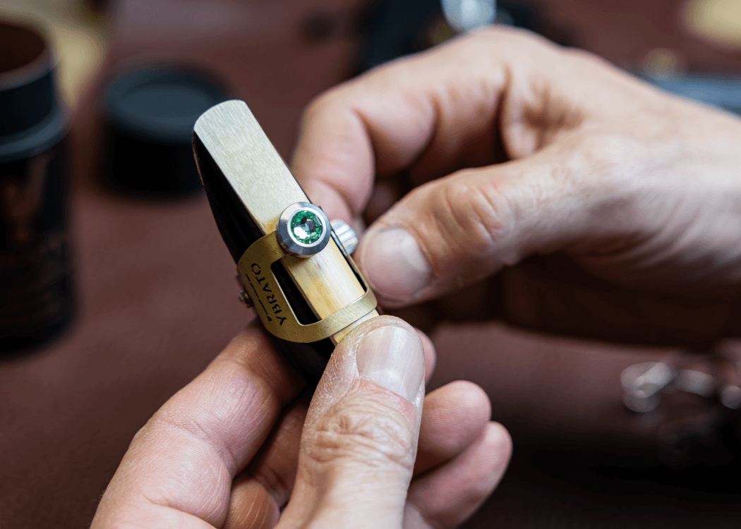 Craftsman assembling a YBRATO ligature with a custom Swarovski crystal screw onto a mouthpiece, illustrating personalization