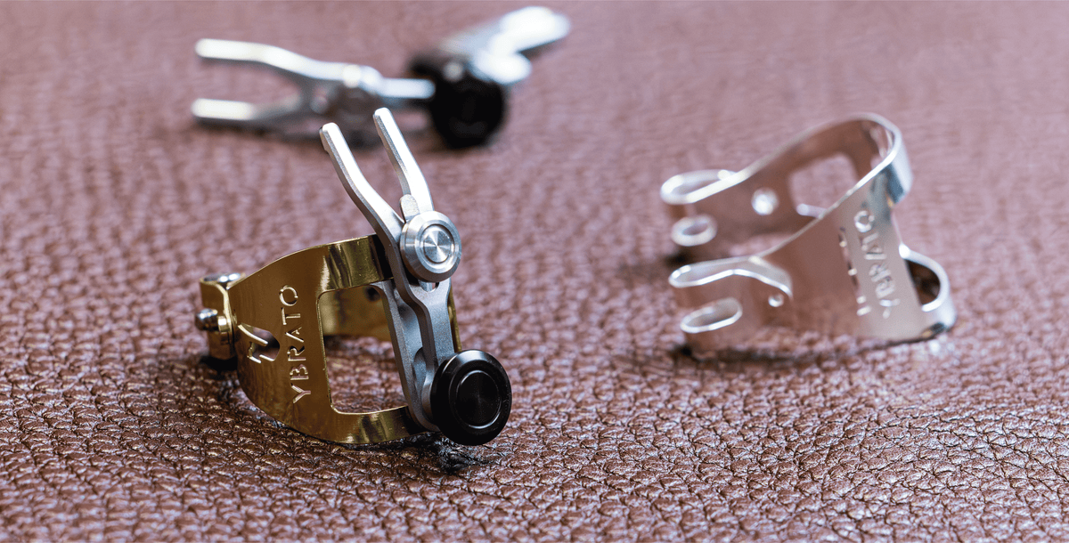 Showcase of gold and silver Ybrato saxophone ligatures on leather, demonstrating the different high-quality finishes and precision engineering of the SweetSpot series.