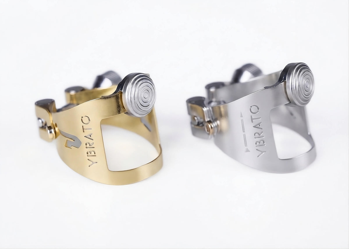 YBRATO ReedReflector ligatures in gold lacquer and silver-plated finish, CNC-milled reflector with dual rails and left/right centering thread, for saxophone and clarinet mouthpieces